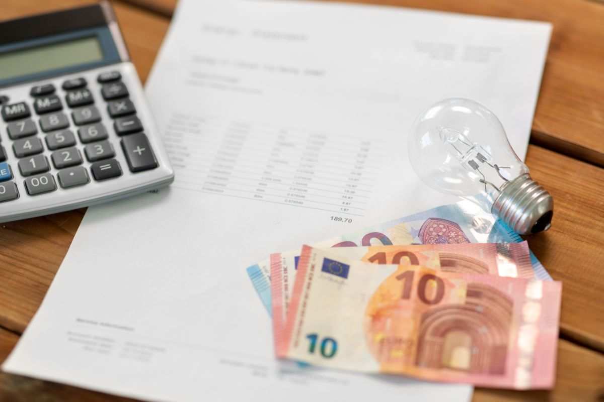 bolletta della corrente, soldi, lampadina e calcolatrice