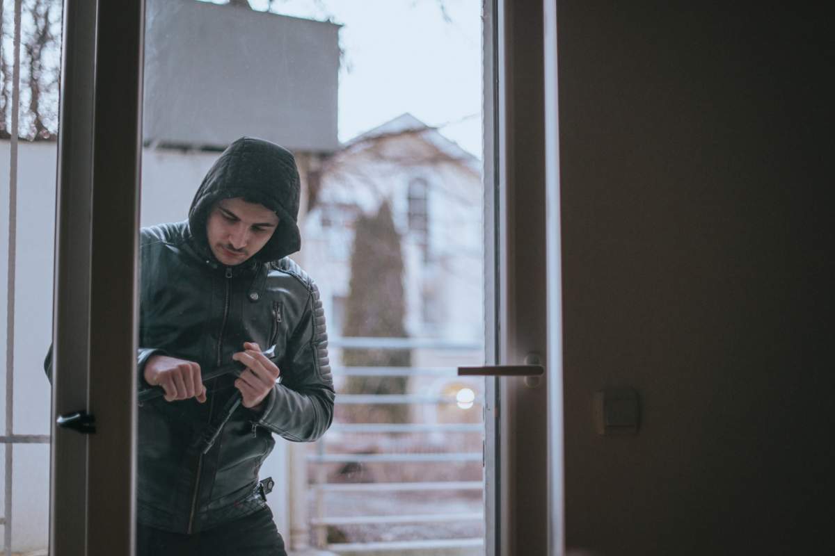 uomo scassina una porta 