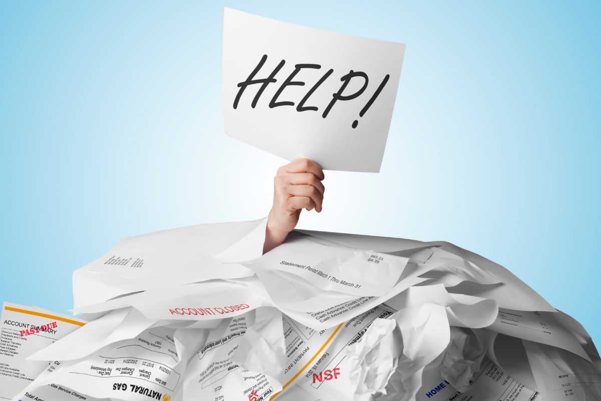persona sommersa da documenti con cartello help