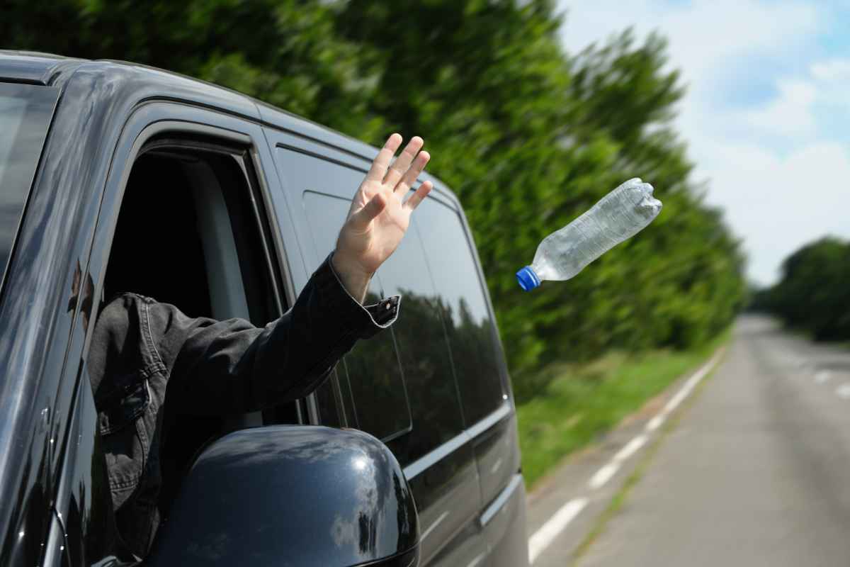 persona getta bottiglia dall'automobile