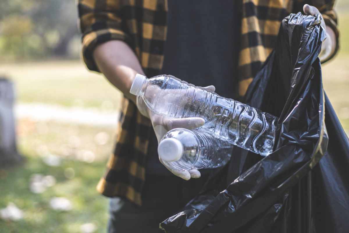 persona getta bottiglia di plastica