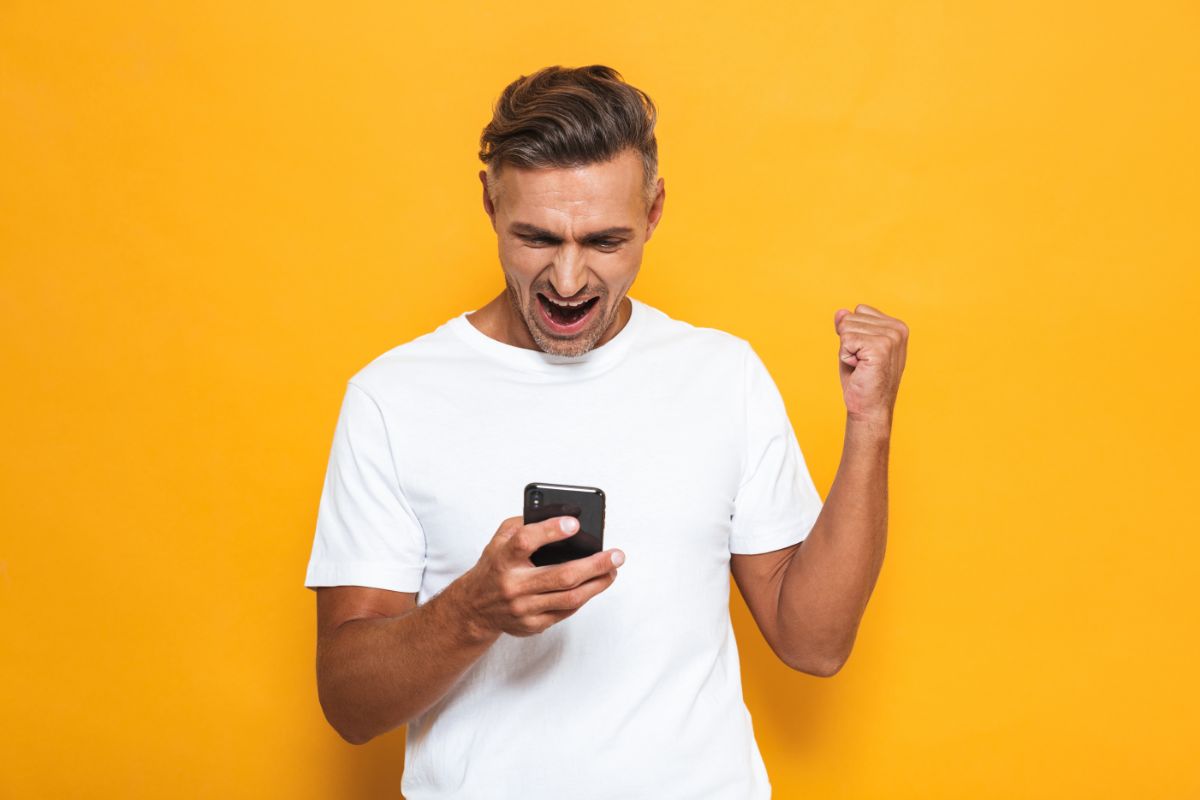 uomo esulta con smartphone in mano
